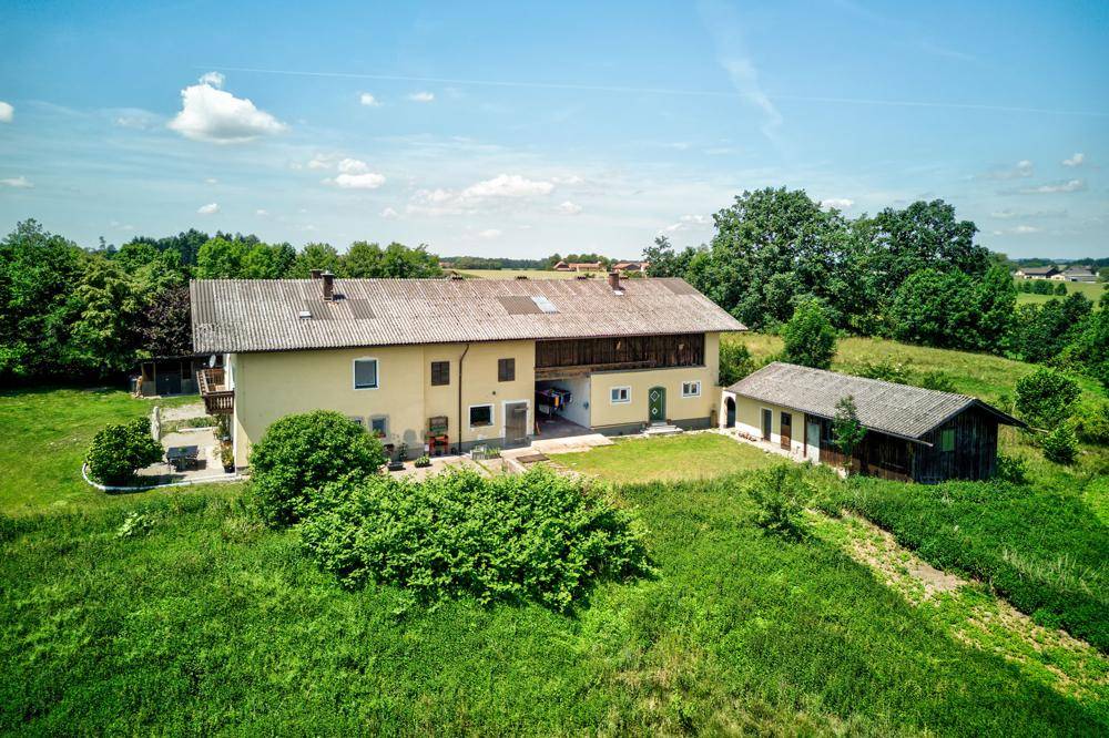 Ansicht des Landhauses von der Seite mit weitläufigen Grünflächen und einem Nebengebäude.
