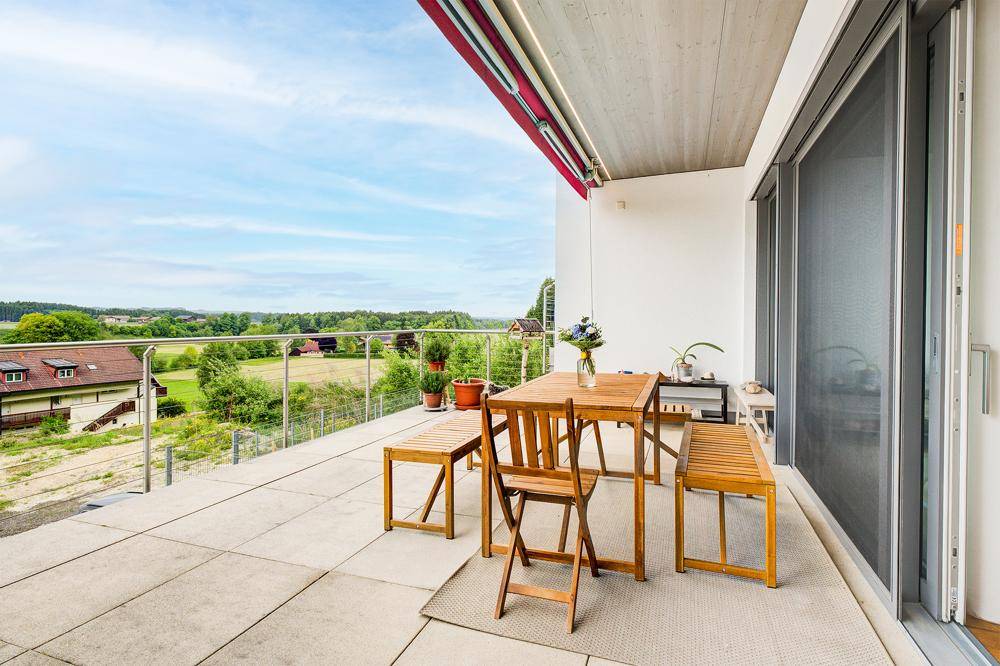 Große Terrasse mit Holztisch und Bänken, ideal für Mahlzeiten im Freien mit schöner Aussicht.