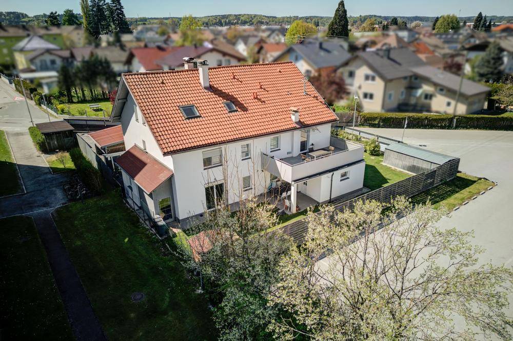 Luftaufnahme eines Einfamilienhauses mit rotem Ziegeldach und umliegender Wohnsiedlung.