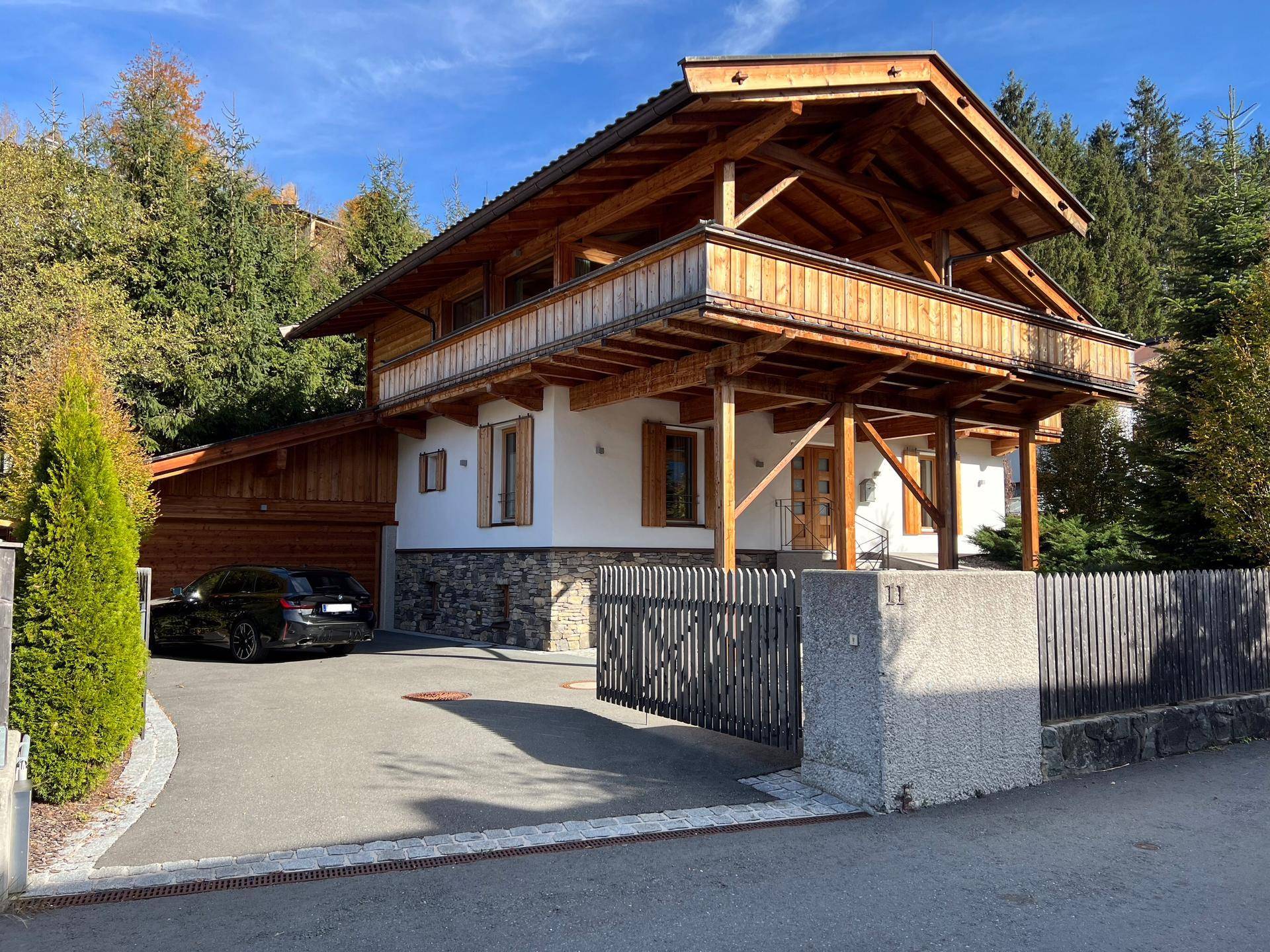 Attraktives Chalet im alpinen Stil mit Holzfassade, Steinelementen und gepflegter Auffahrt.