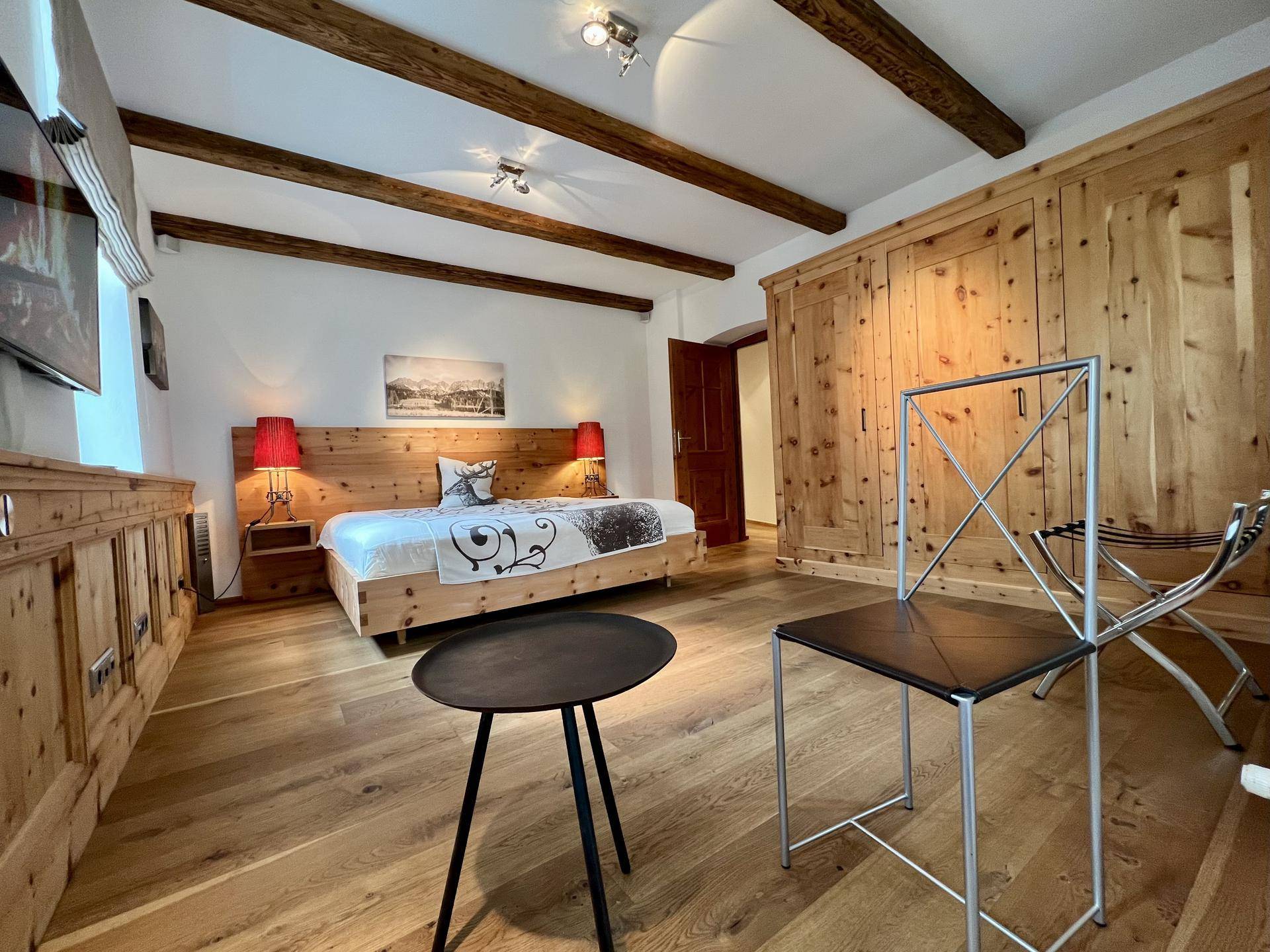 Helles Schlafzimmer mit Holzbalken, Parkettboden und integrierten Holzschränken für viel Stauraum.