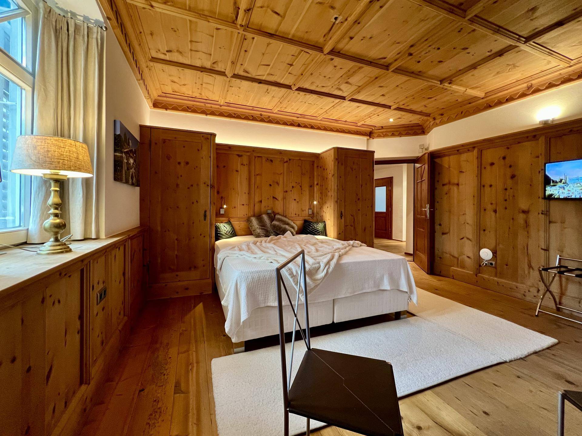 Schlafzimmer mit Holztäfelung, Holzboden und einem großen Bett, das eine warme Atmosphäre schafft.