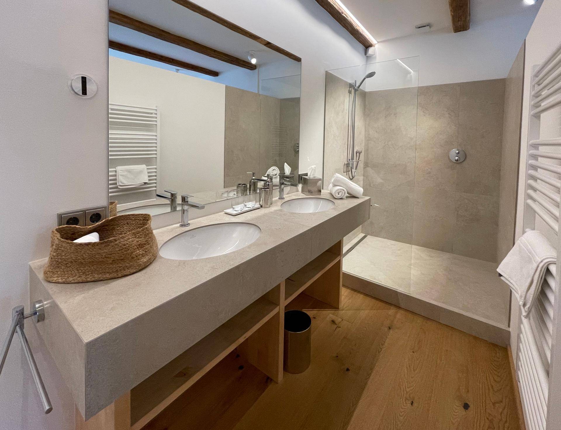 Modernes Badezimmer mit Doppelwaschbecken, begehbarer Dusche und beheiztem Handtuchhalter.