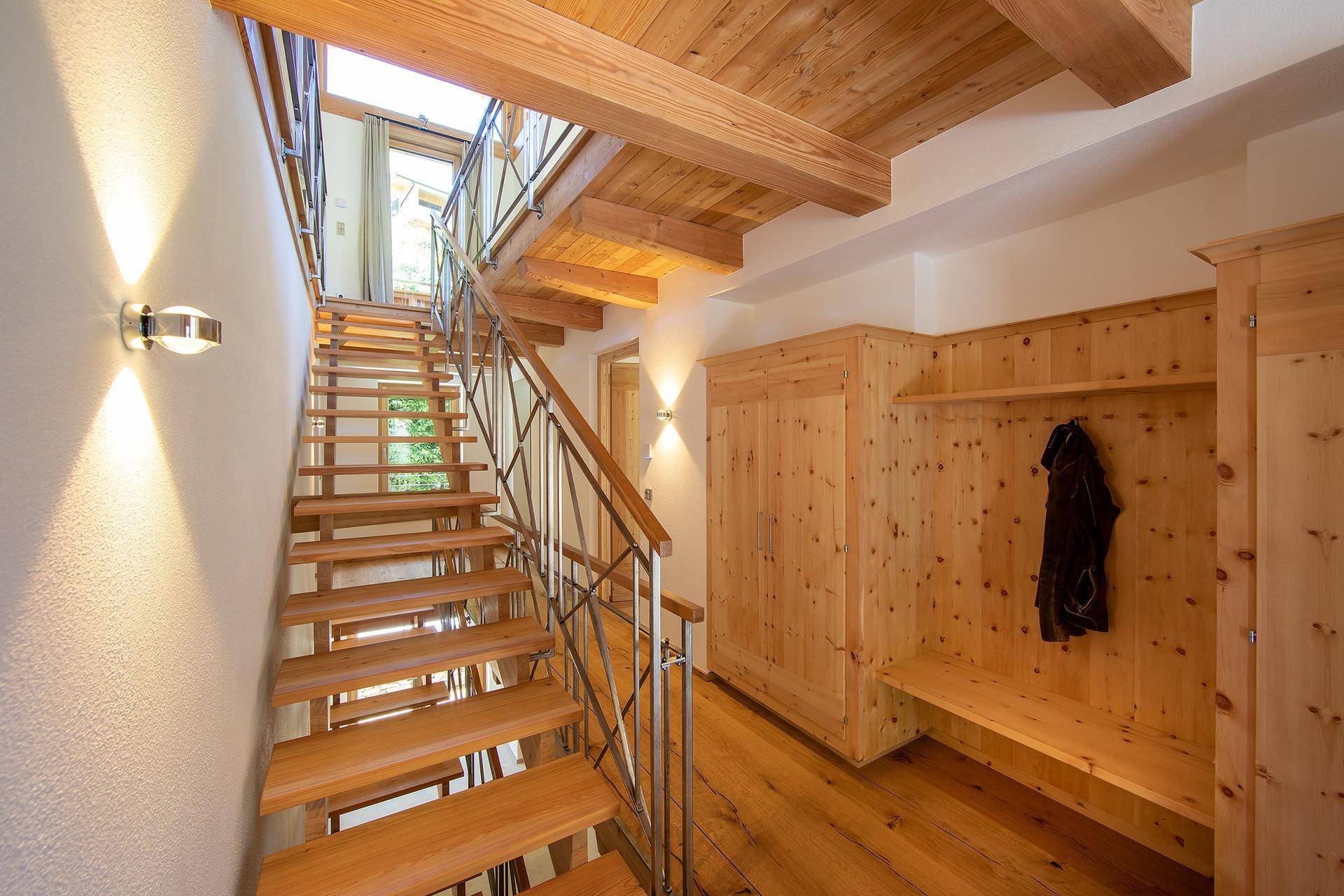 Heller Eingangsbereich mit offener Holztreppe und praktischen Einbauschränken aus hellem Holz.