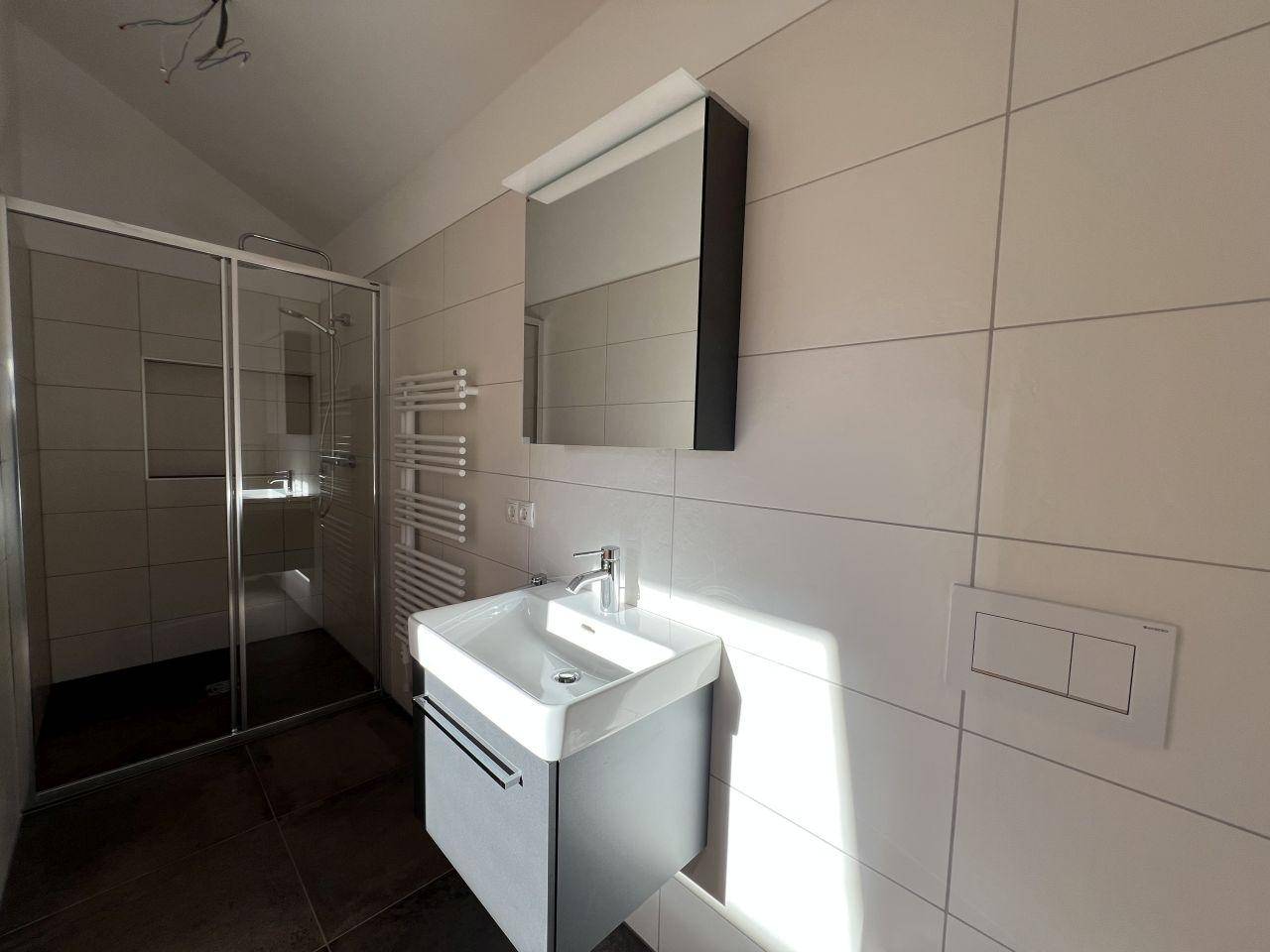 Helles Badezimmer mit begehbarer Dusche, Waschtisch und beheiztem Handtuchhalter.