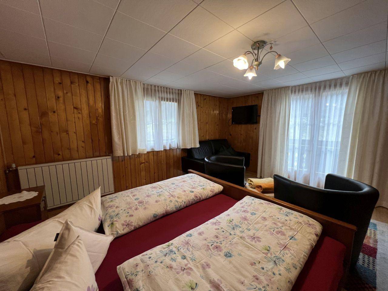 Gemütliches Schlafzimmer mit Holztäfelung, zwei Einzelbetten und Blick ins Grüne.