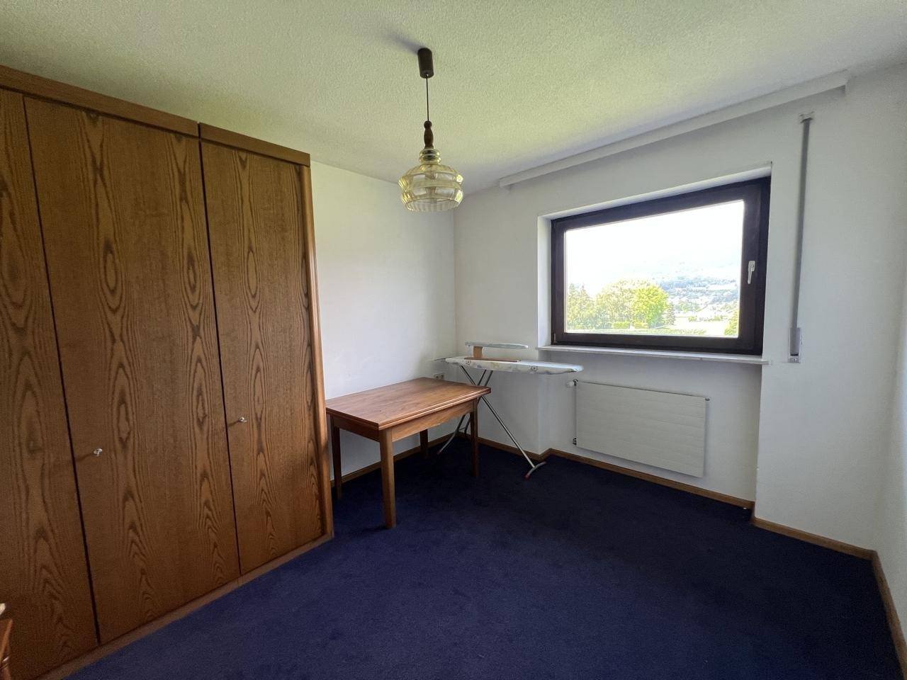 Schlafzimmer mit großem Einbauschrank, Teppichboden und Fenster mit Weitblick.