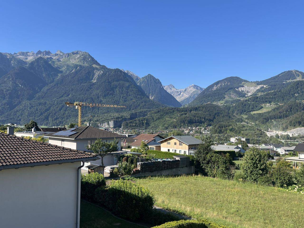 Weitläufiger Blick über eine Wohnsiedlung mit beeindruckender Bergkulisse im Hintergrund.