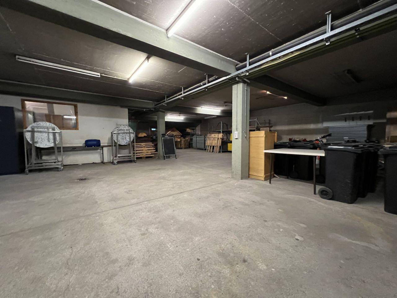 Großer, funktionaler Lagerraum mit Betonboden und sichtbaren Deckeninstallationen, ideal für gewerbliche Nutzung.