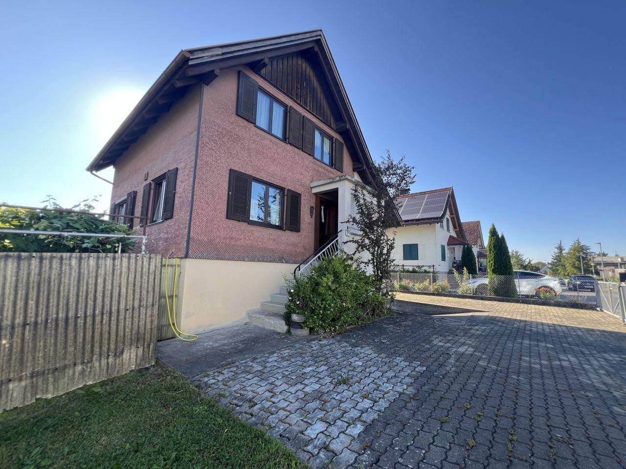 Vorderansicht des Hauses mit Eingangsbereich und gepflasterter Zufahrt.