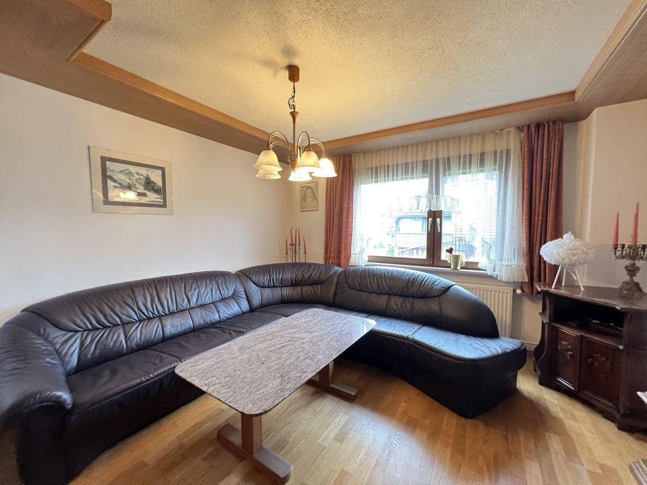 Wohnzimmer mit bequemer Ledercouch und traditionellen Holzmöbeln.