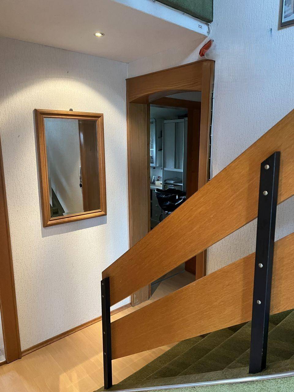 Heller Flurbereich mit Holzrahmen und einem Spiegel an der Wand.
