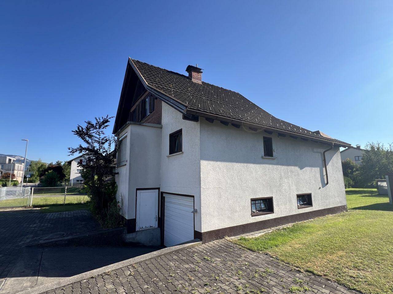 Seitenansicht des Hauses mit Garagenzufahrt und gepflastertem Bereich.