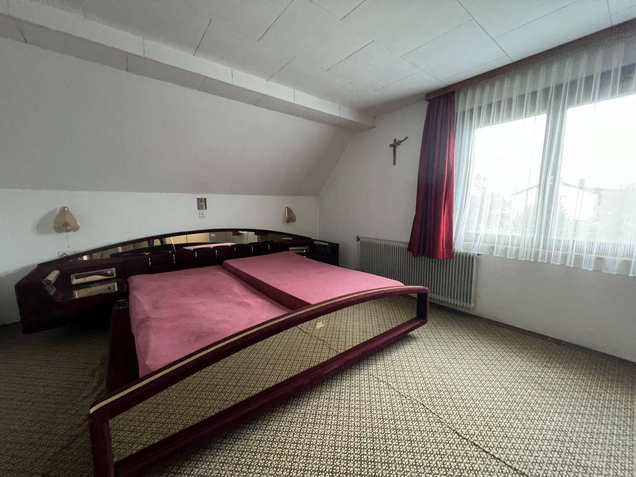 Schlafzimmer mit Dachschräge, großem Bett und Teppichboden in traditionellem Stil.