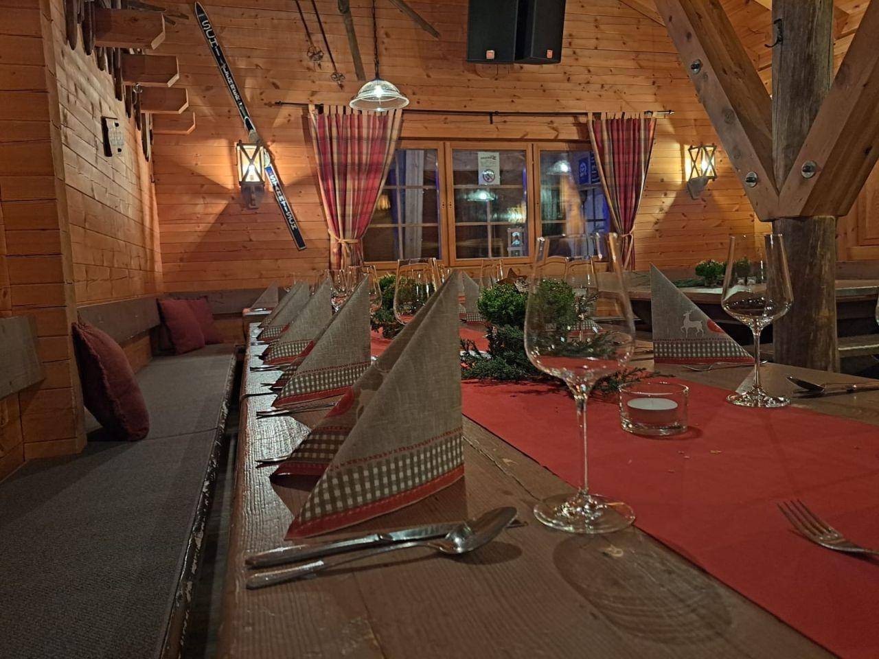 Nahaufnahme eines festlich gedeckten Holztisches mit Gläsern und Servietten in einem rustikalen Ambiente.