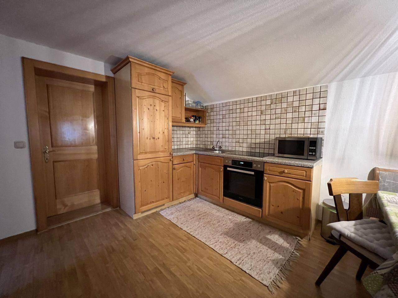 Funktionale Küche mit Holzschränken, integriertem Backofen und gefliestem Wandbereich.