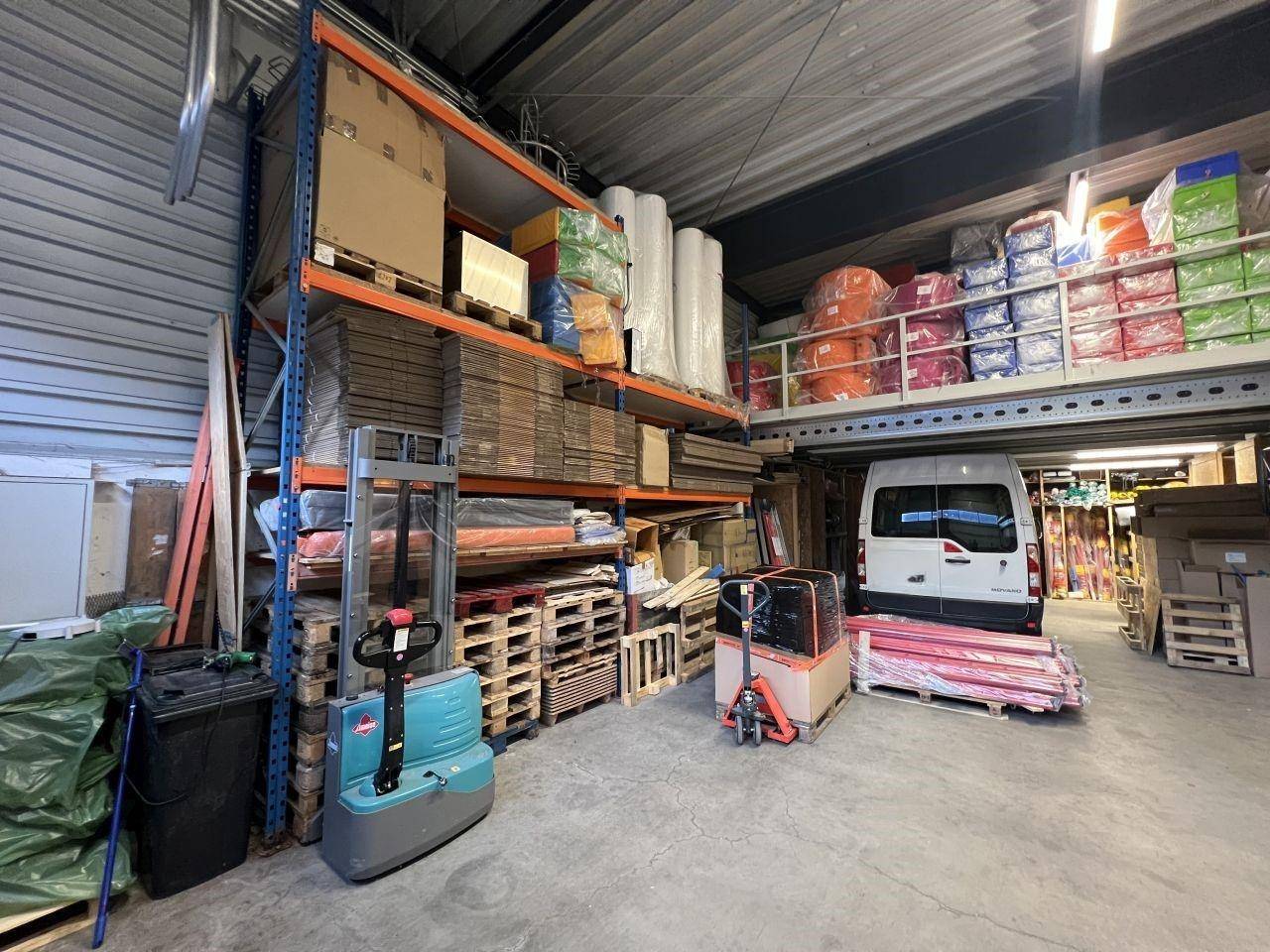 Geräumige Lagerhalle mit hohen Regalen, Gabelstaplern und verschiedenen Waren auf Paletten.