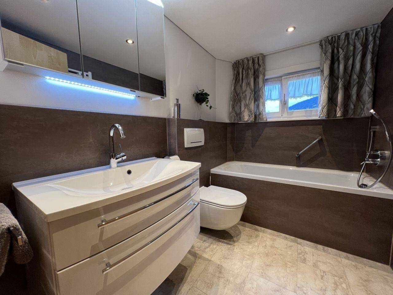 Modernes Badezimmer mit Badewanne, Waschtisch und Spiegelschrank, in neutralen Farbtönen.