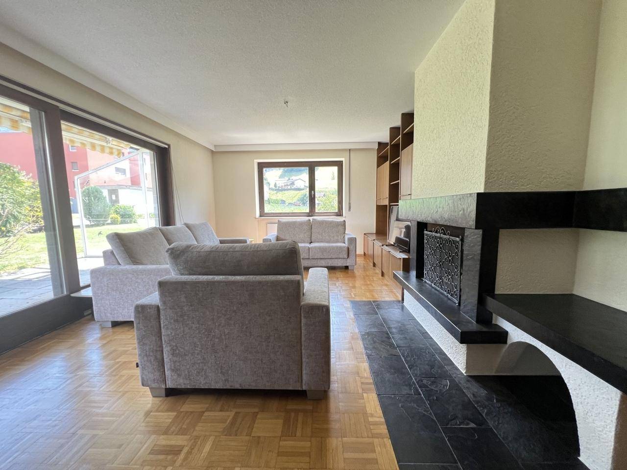 Gemütliches Wohnzimmer mit Kamin, Parkettboden und Blick ins Grüne.