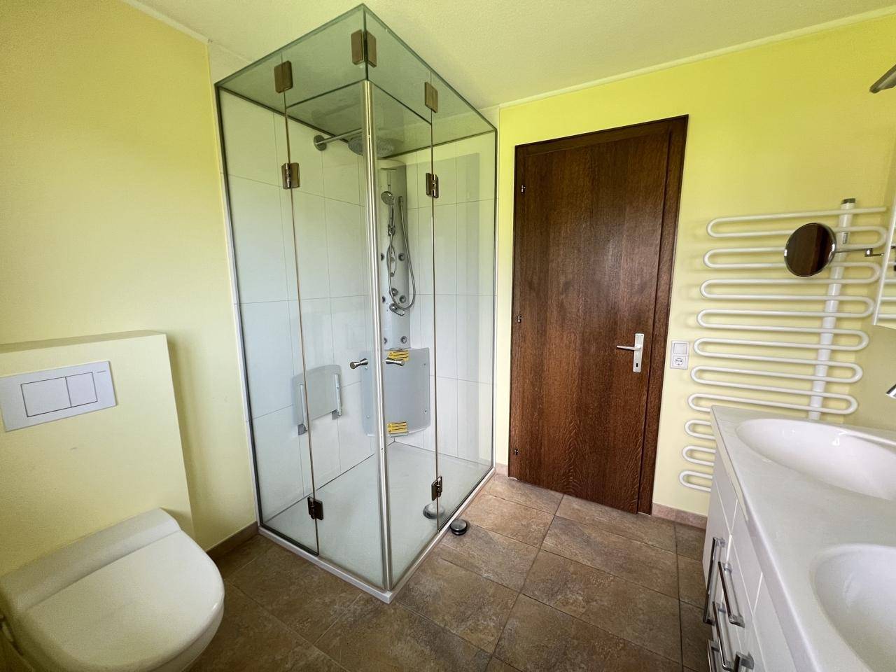 Badezimmer mit moderner Glasdusche, wandhängendem WC und beheiztem Handtuchhalter.