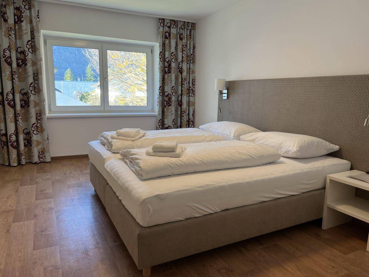 Gemütliches Schlafzimmer mit Doppelbett, Fenster und Blick auf die grüne Umgebung.