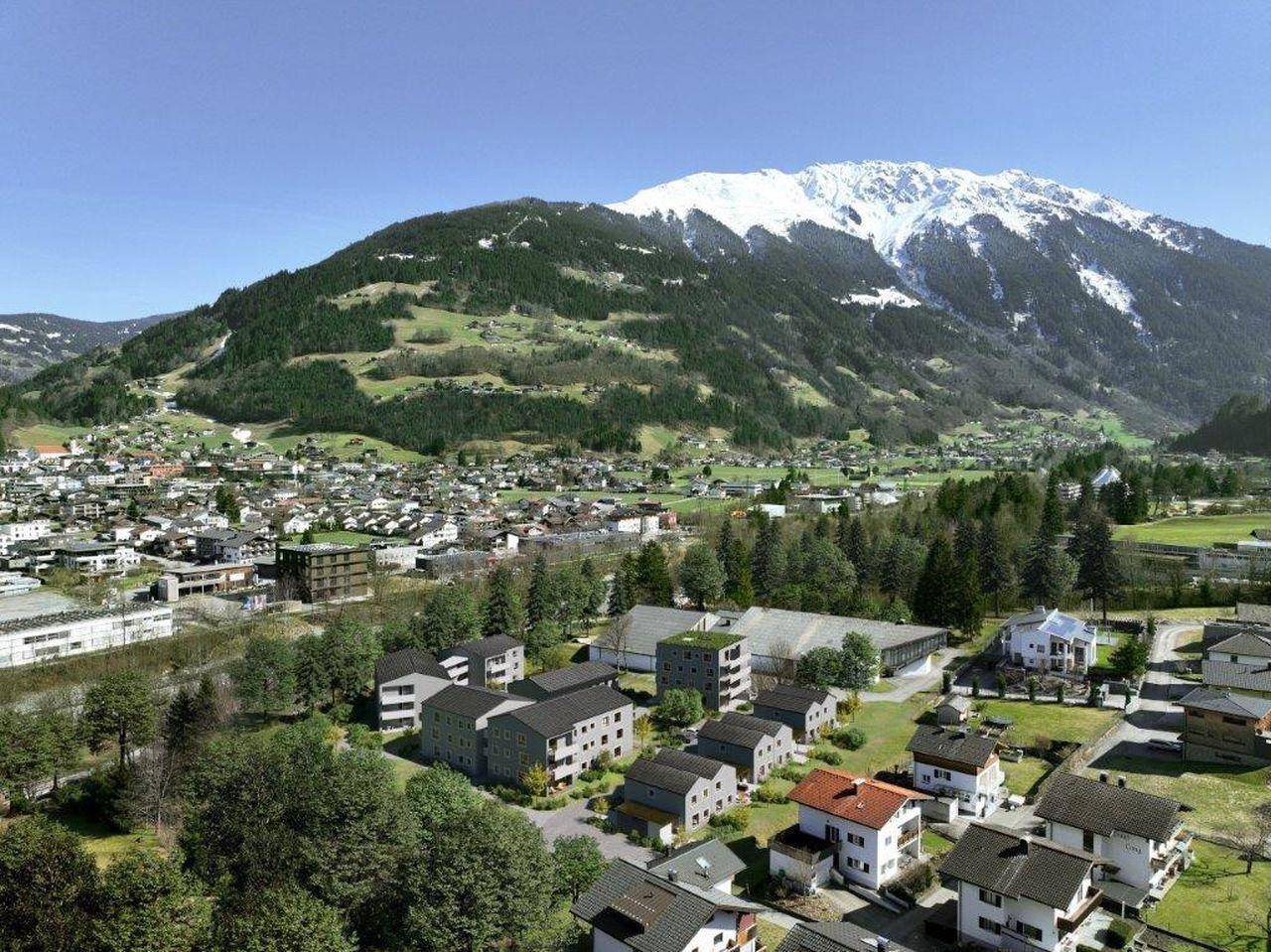 Luftaufnahme einer Siedlung am Fuße eines schneebedeckten Berges mit weitem Blick.