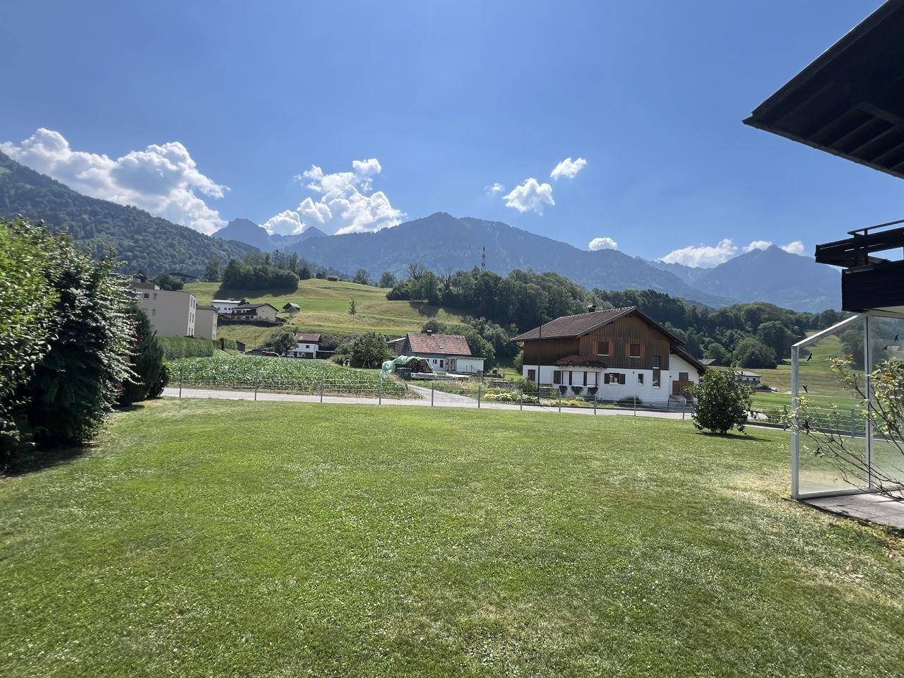 Panoramablick vom Grundstück auf die grüne Landschaft und die majestätischen Berge.
