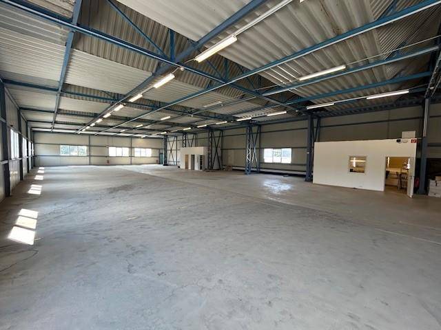 Helle und geräumige Lagerhalle mit vielen Fenstern, Betonboden und hoher Industriedecke.