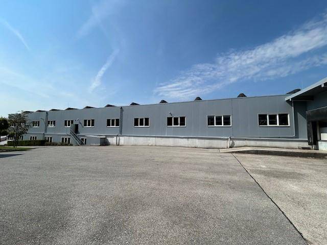 Lange Fassade des modernen Gewerbegebäudes mit zahlreichen Fenstern und weitläufigem Parkplatz.