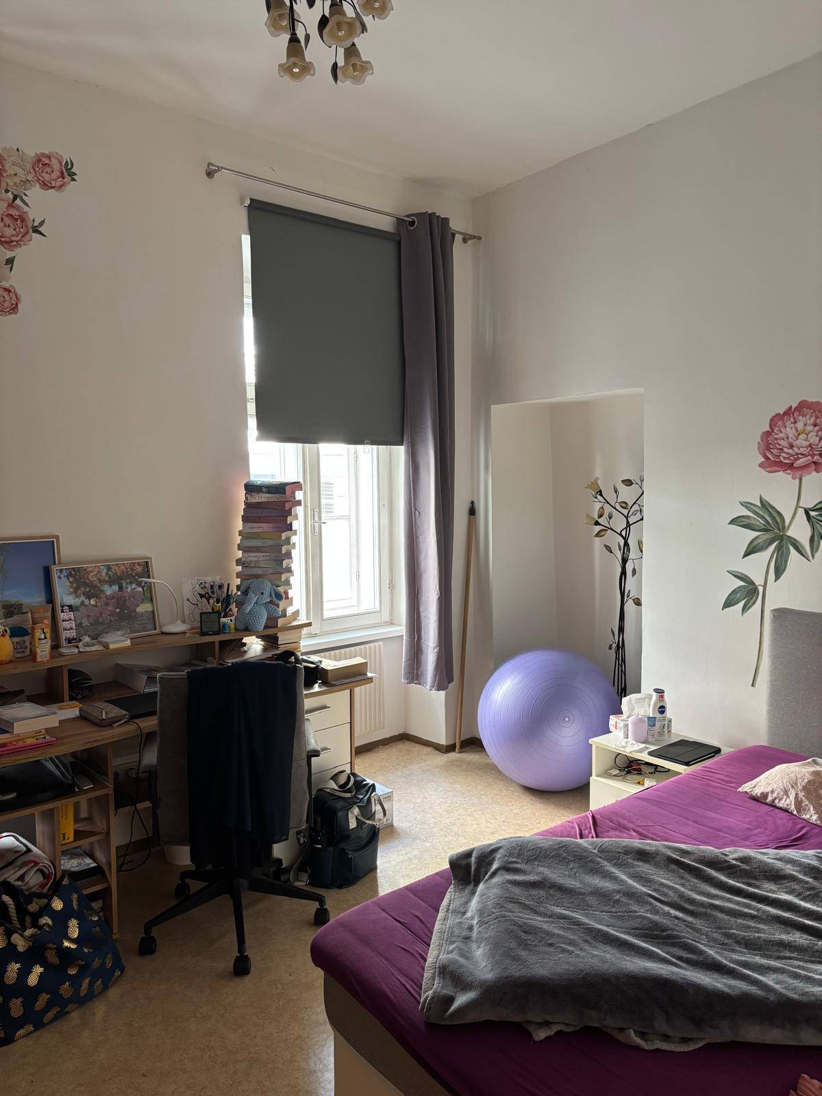 Schlafzimmer mit Bett, Schreibtisch und floralen Wanddekorationen, bietet Platz für persönliche Gestaltung.