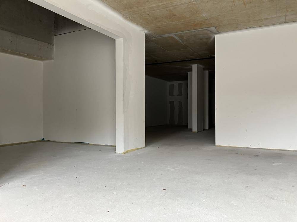 Offener Gewerberaum im Rohbauzustand mit tragenden Säulen und unfertigen Wänden.