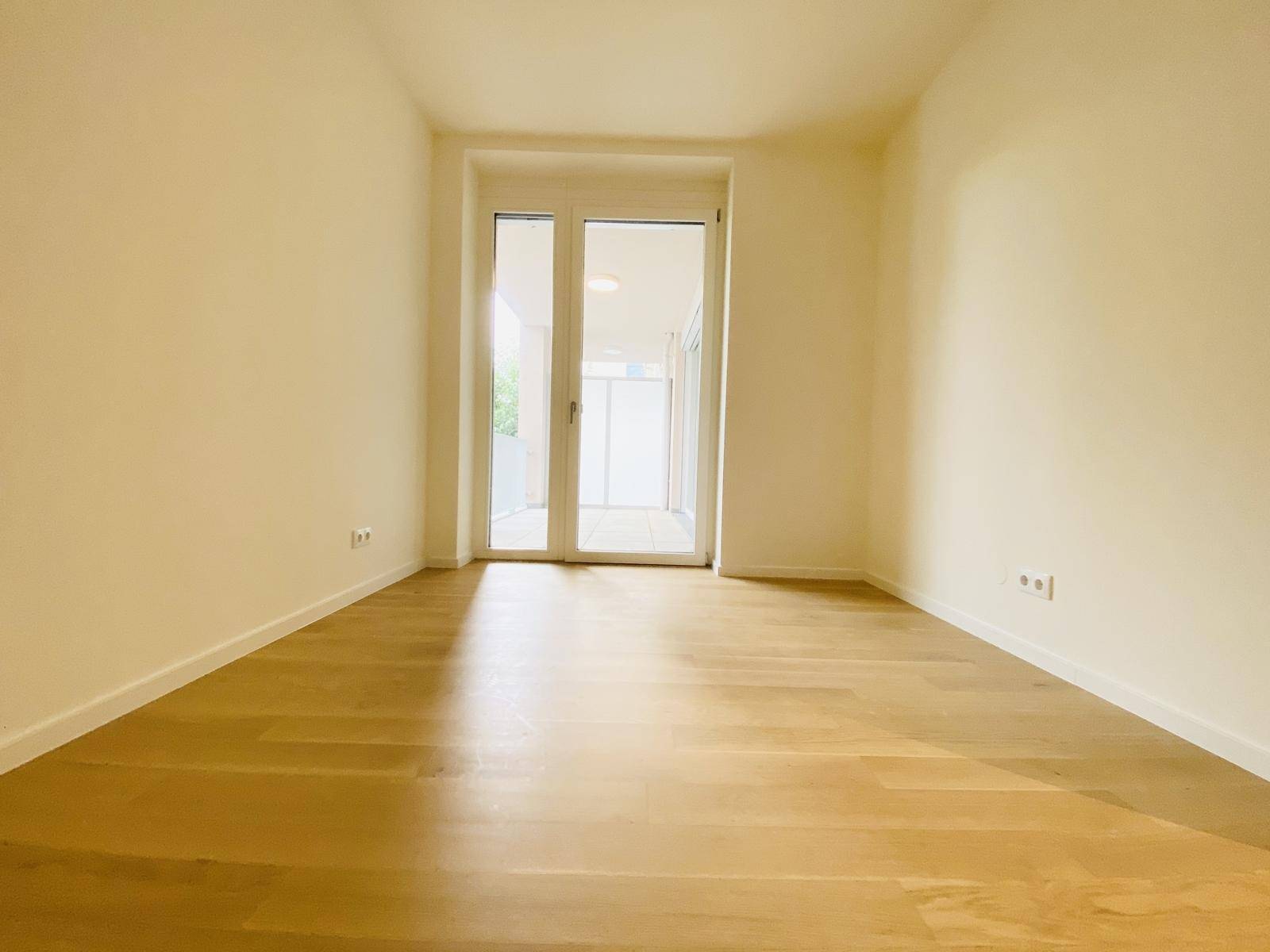 Freundlicher Raum mit Parkettboden und Zugang zu einem weiteren Bereich.