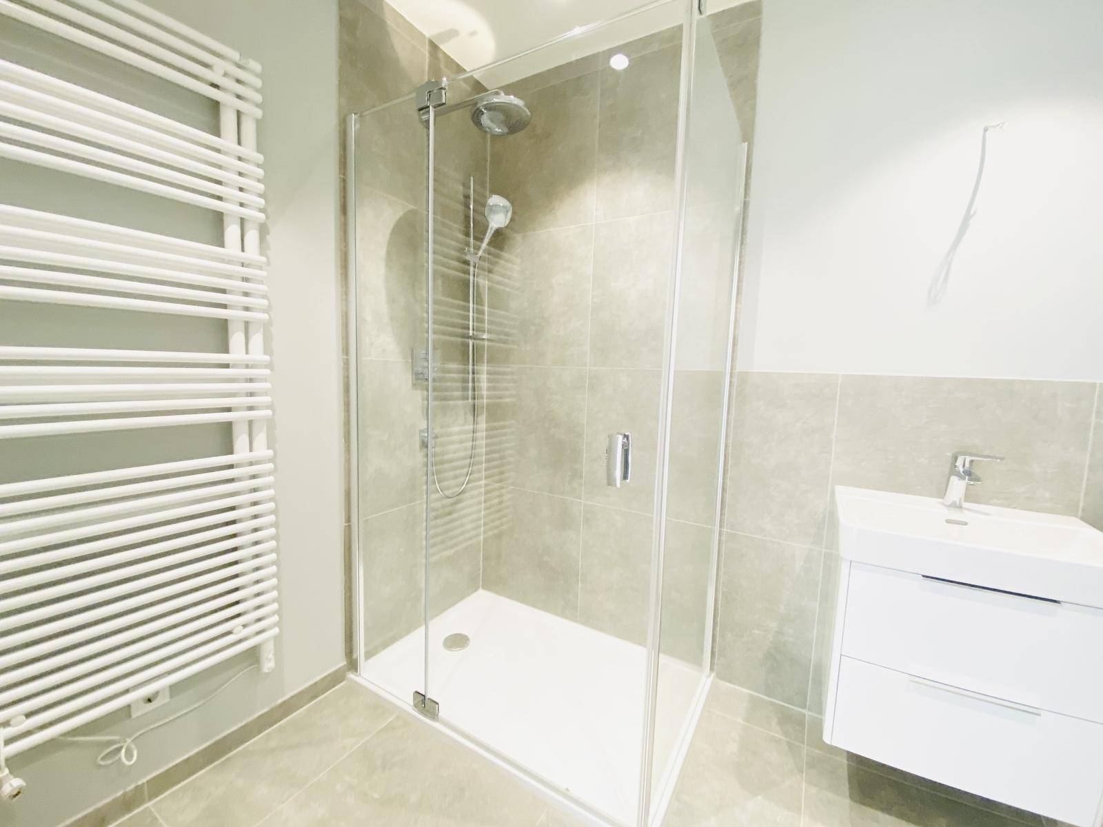 Detaillierte Ansicht der modernen Glasdusche mit Regenbrause und dem praktischen Handtuchheizkörper.