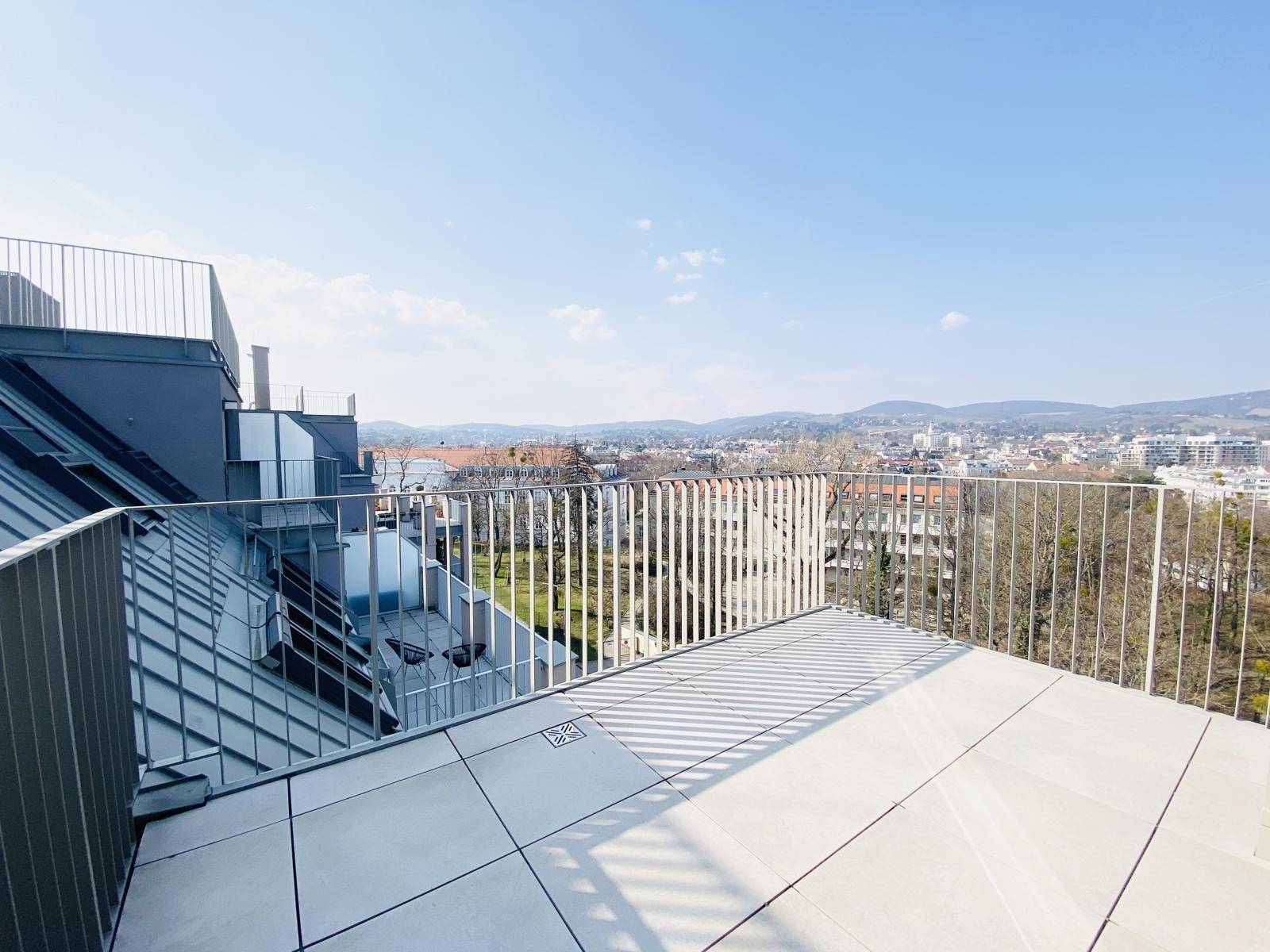 Dachterrasse mit moderner Architektur, Fliesenboden und weitem Blick über die Umgebung.