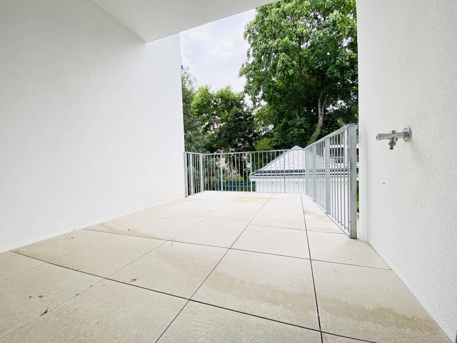 Heller Balkon mit Fliesenboden und Blick ins Grüne, ideal zum Entspannen.