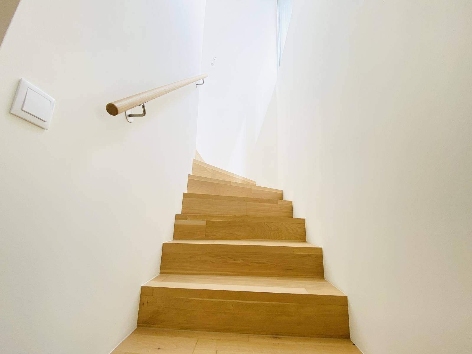 Elegante Holztreppe mit schlichtem Handlauf, verbindet die verschiedenen Ebenen der Wohnung.
