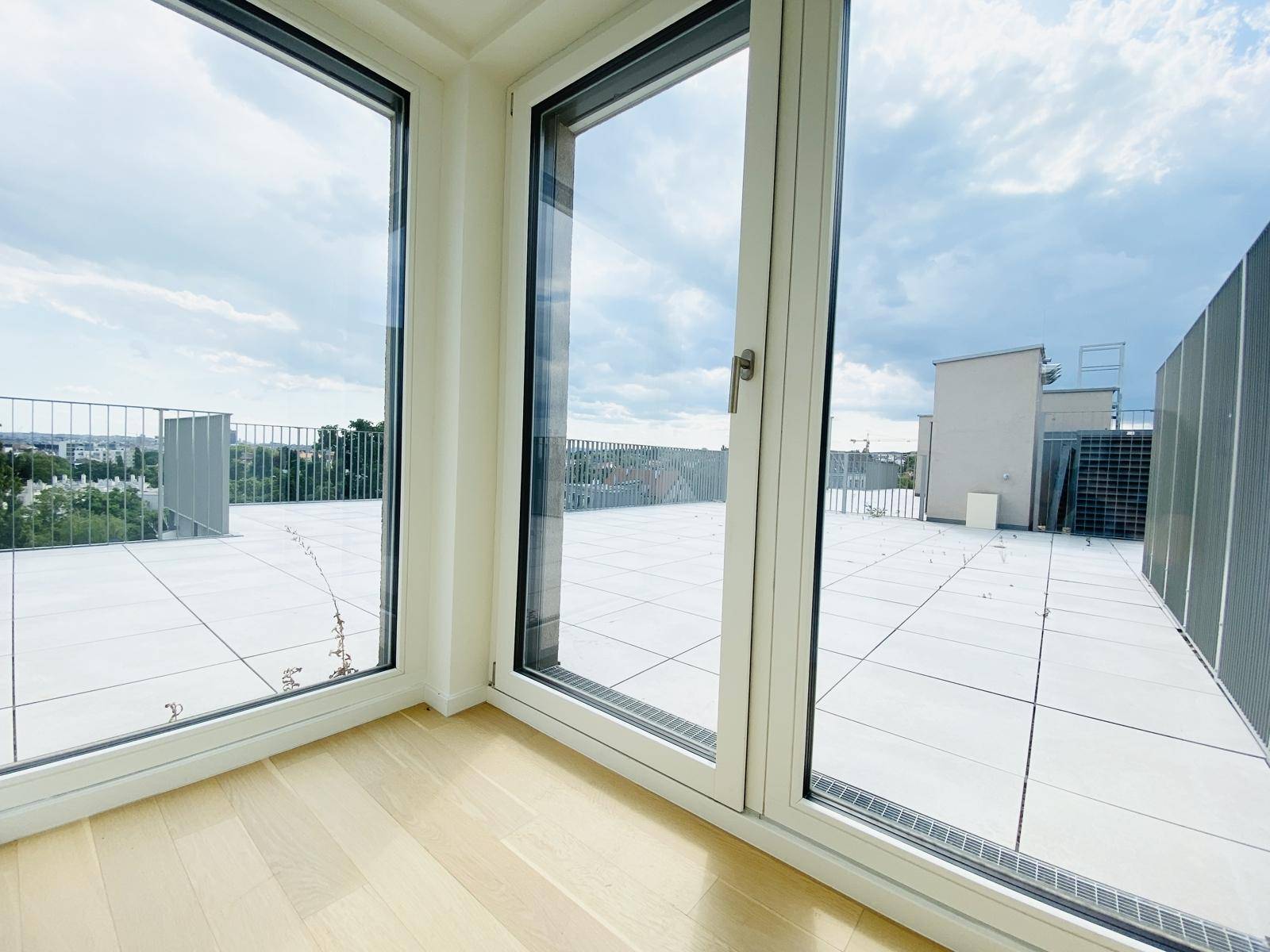 Große Fensterfront mit Blick auf die weitläufige Dachterrasse, lässt viel Licht herein.