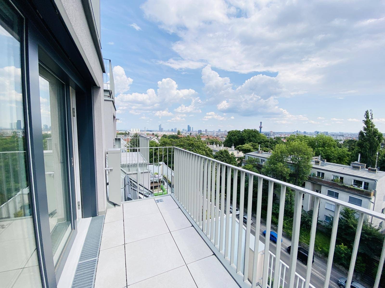 Heller Balkon mit Schiebetürzugang und Stadtblick, ideal für entspannte Stunden im Freien.