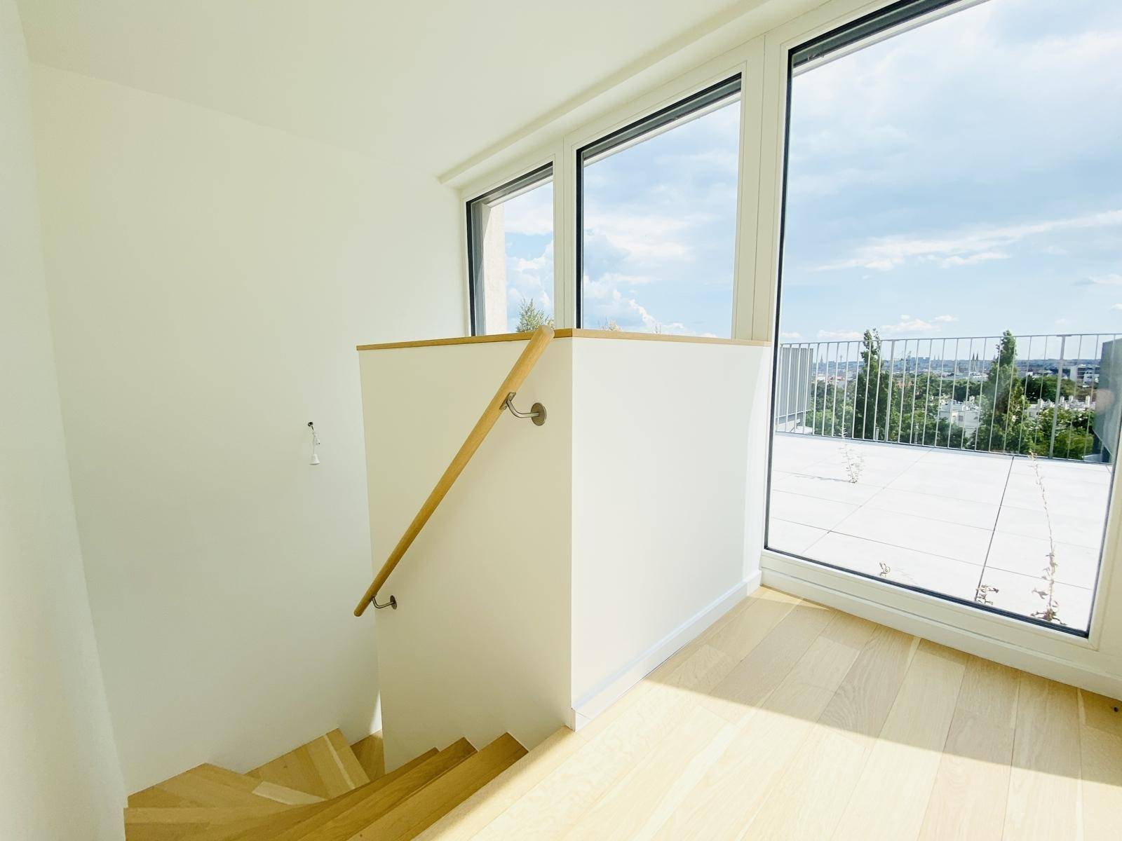 Treppenabsatz mit großen Fenstern und Zugang zur Dachterrasse, bietet hellen Übergangsbereich.