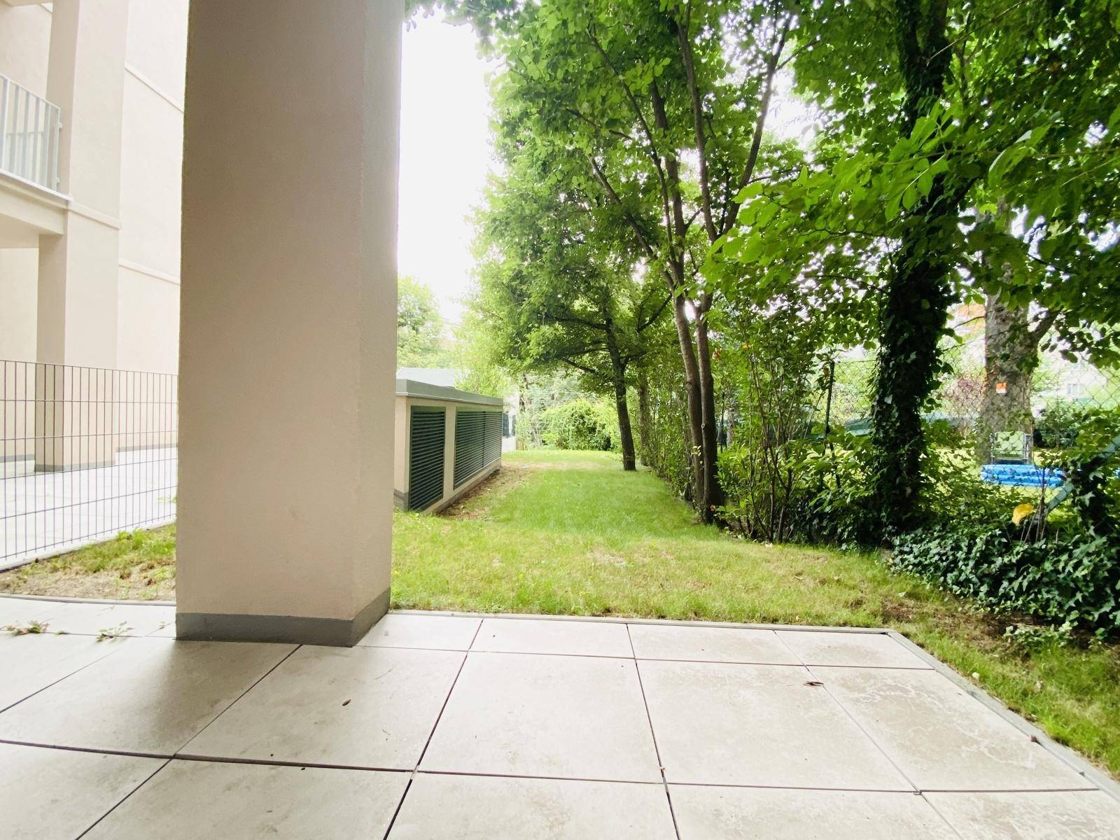 Ruhiger Gartenbereich mit viel Grün und altem Baumbestand, direkt an die Terrasse angrenzend.