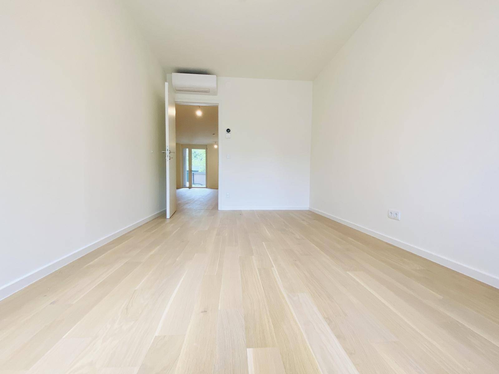 Helles Schlafzimmer mit Parkettboden und installierter Klimaanlage für angenehmes Raumklima.