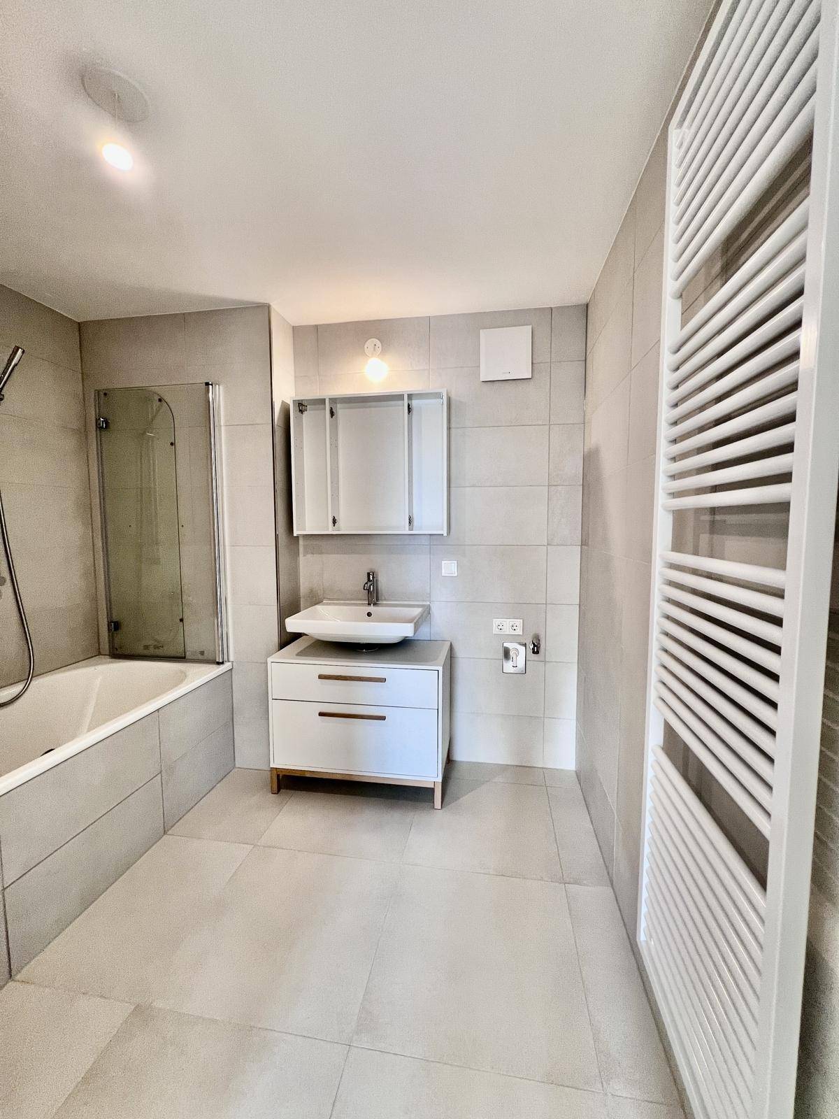 Modernes Badezimmer mit Badewanne, Waschtisch und beheiztem Handtuchhalter.