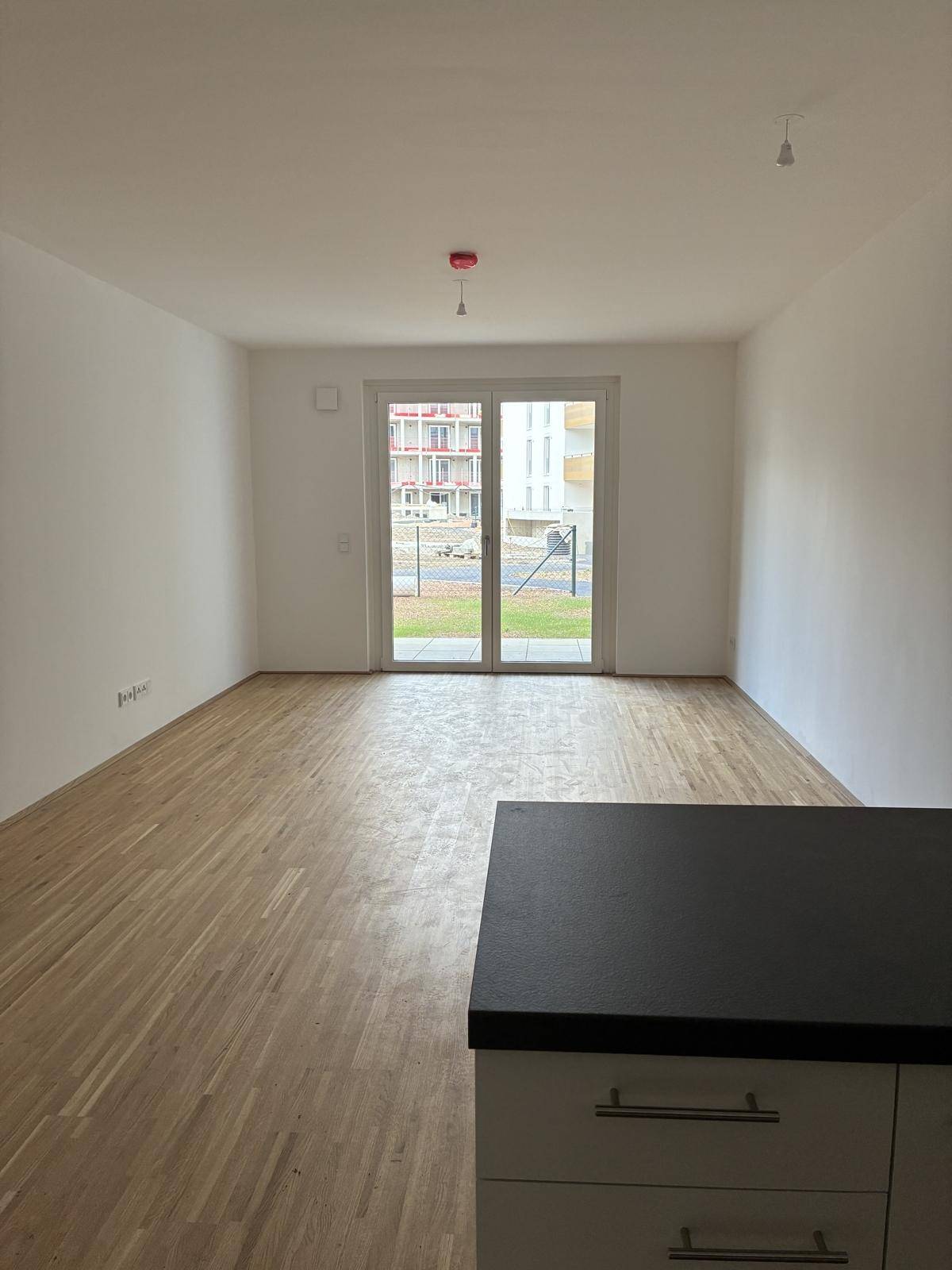 Heller Wohnbereich mit Parkettboden und Zugang zum Außenbereich.