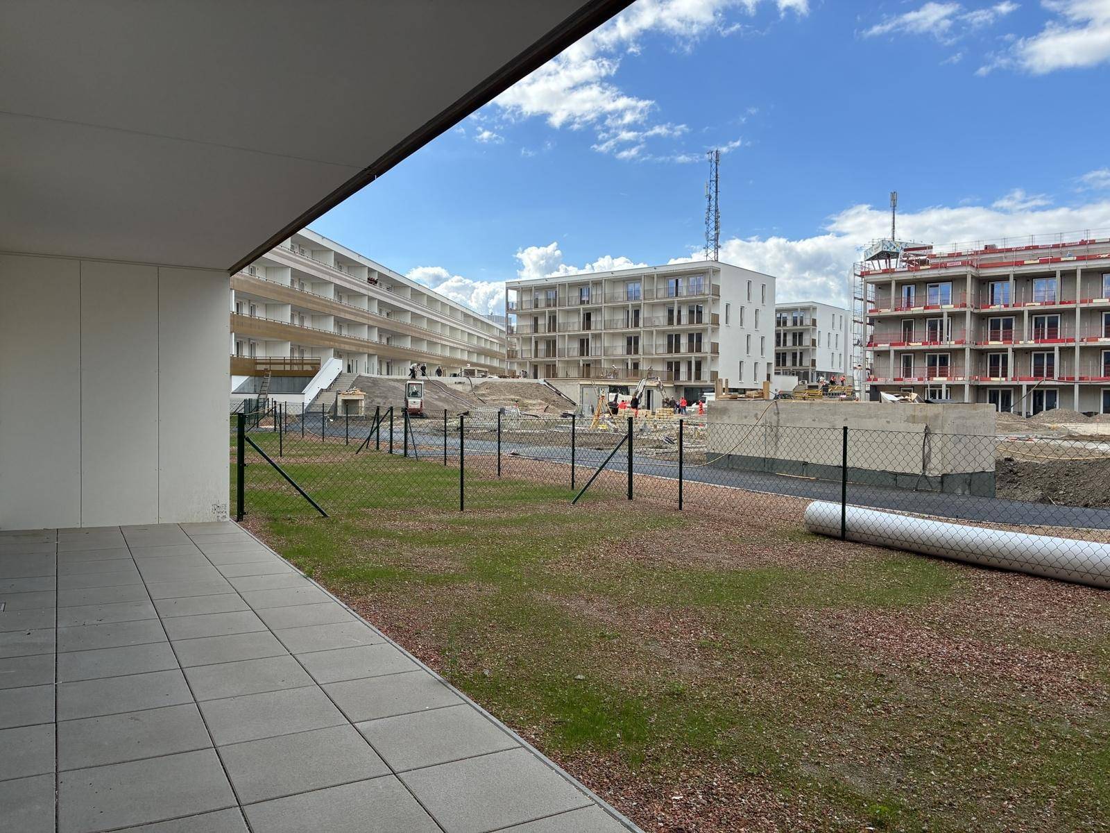 Weitläufige Terrasse mit Blick auf die im Bau befindliche Wohnanlage.