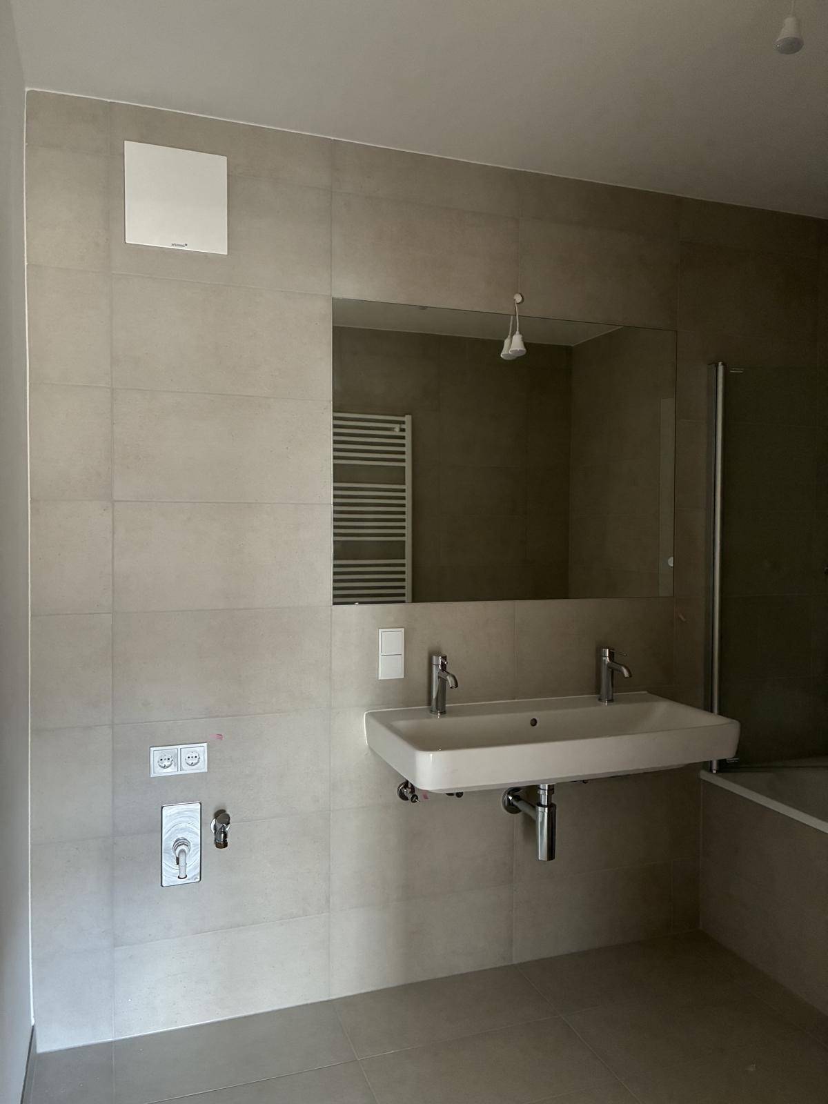 Helles Badezimmer mit großem Spiegel, Doppelwaschbecken und Badewanne.