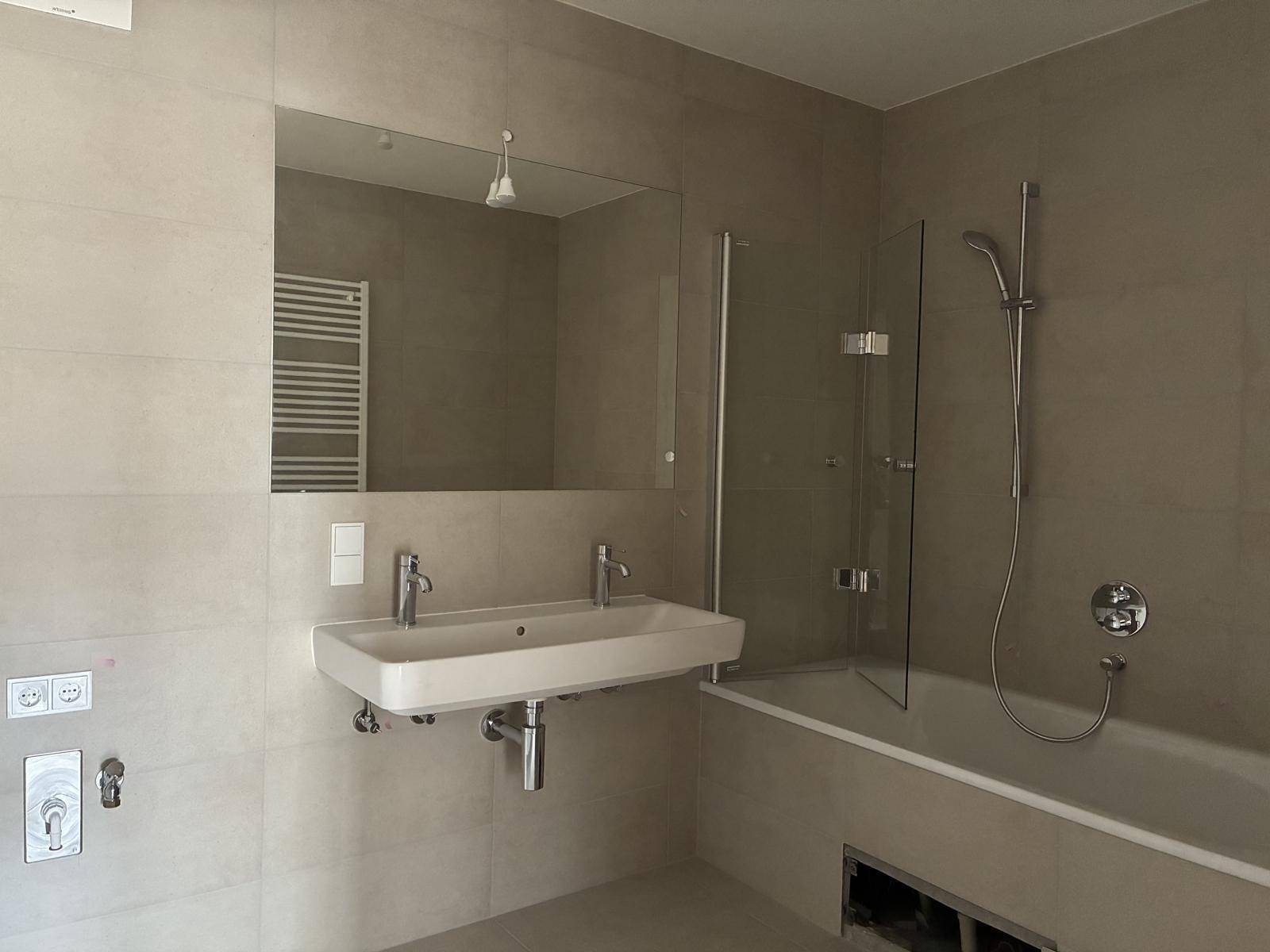 Modernes Badezimmer mit Doppelwaschbecken, Badewanne und beheiztem Handtuchhalter.