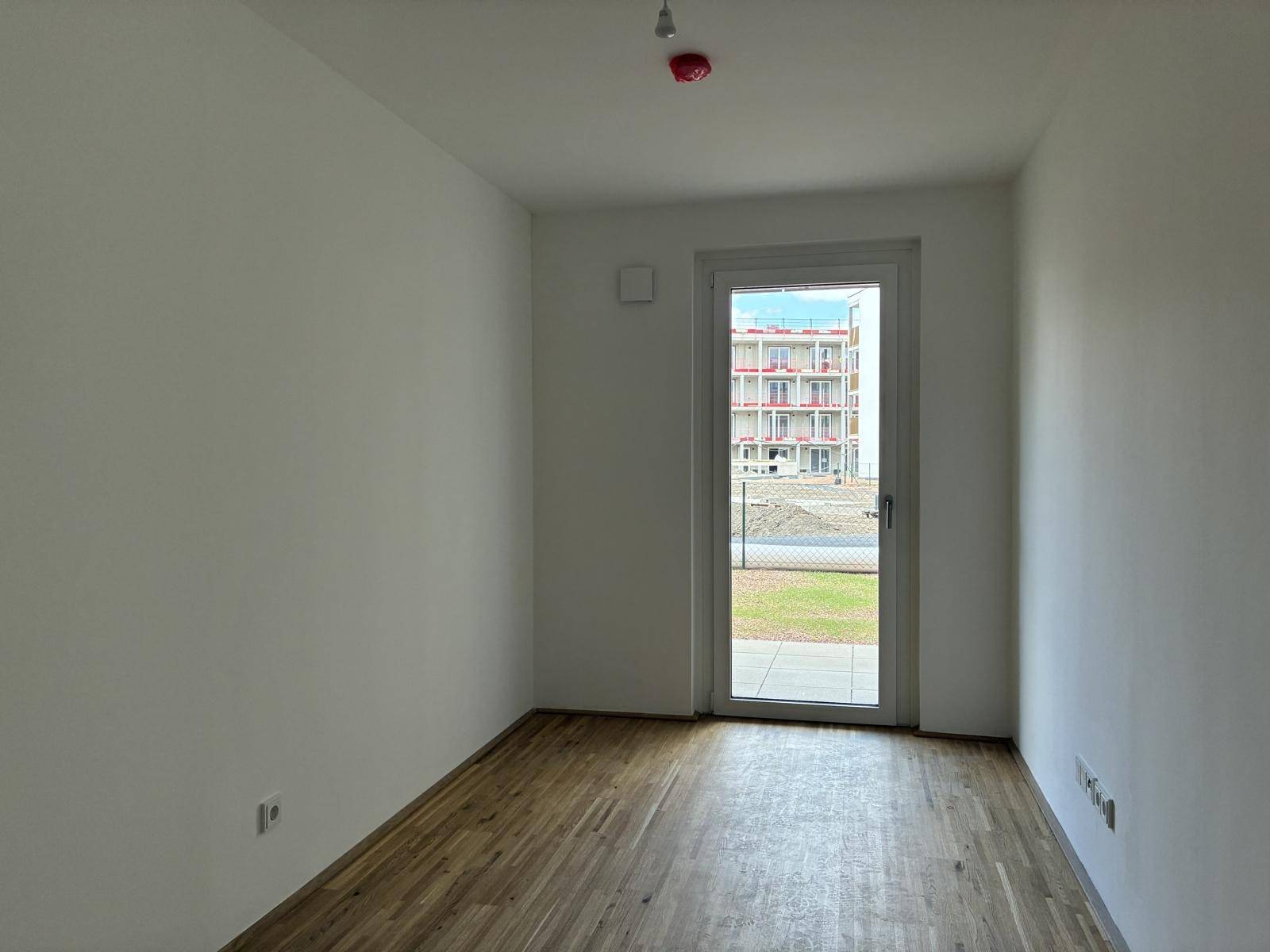 Gemütliches Zimmer mit Parkettboden und Zugang zu einem kleinen Außenbereich.