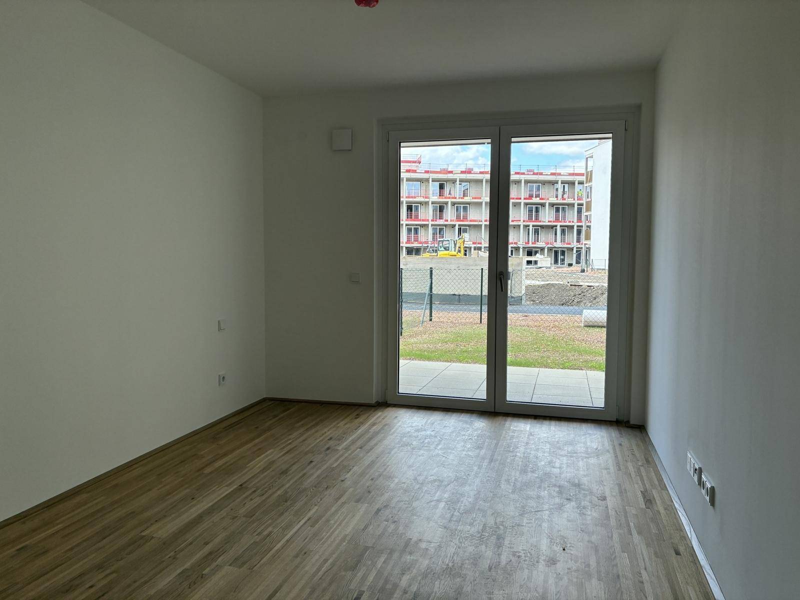 Helles Zimmer mit großem Schiebefenster und Zugang zum Außenbereich.