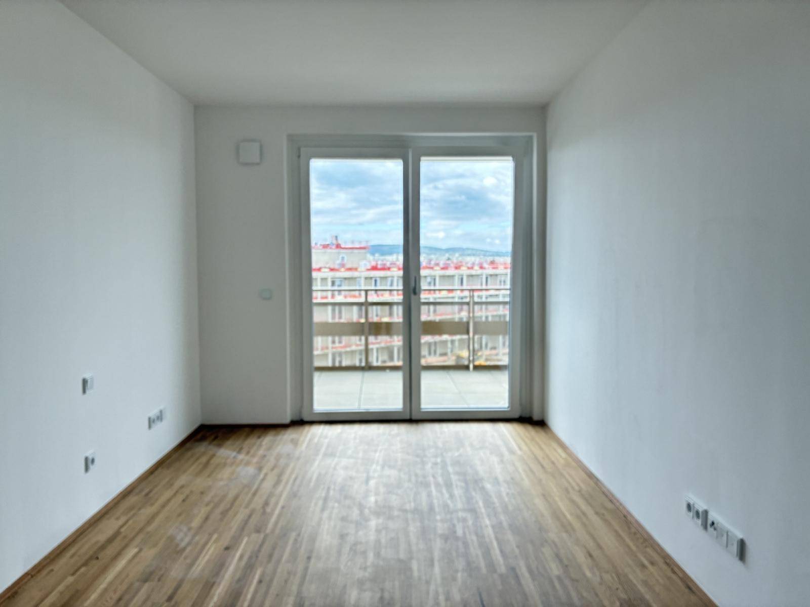 Schlafzimmer mit Holzboden und Zugang zu einem Außenbereich, bietet viel natürliches Licht und Weitblick.