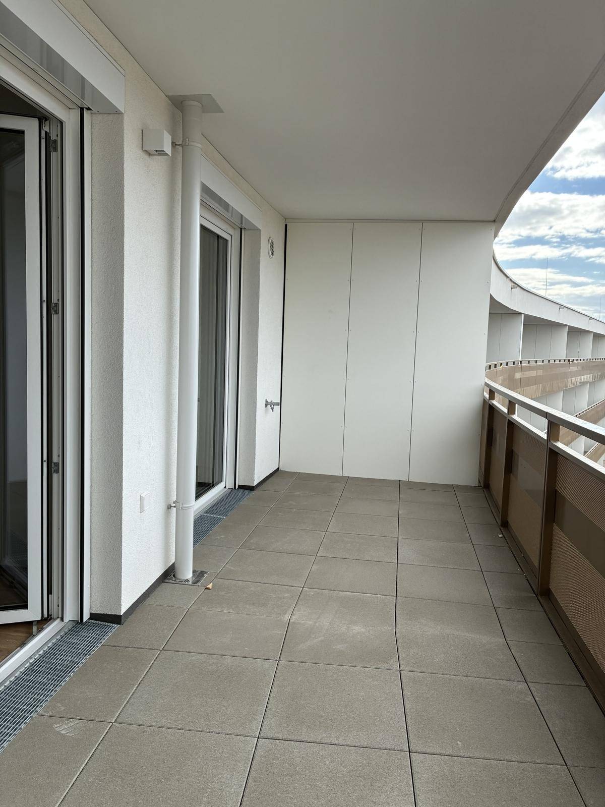 Langer Balkon mit Fliesenboden und moderner Brüstung, ideal für entspannte Stunden im Freien.